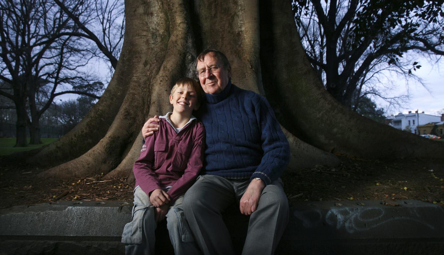 A father & son in front of a large oak tree