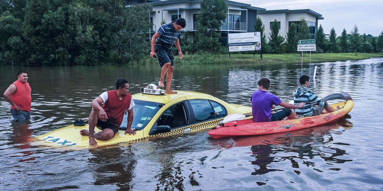 People standing on a taxi in the middle of floods