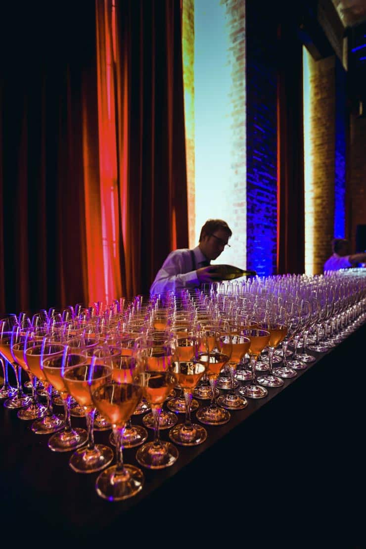 A waiter pours glasses of champagne at a gala event